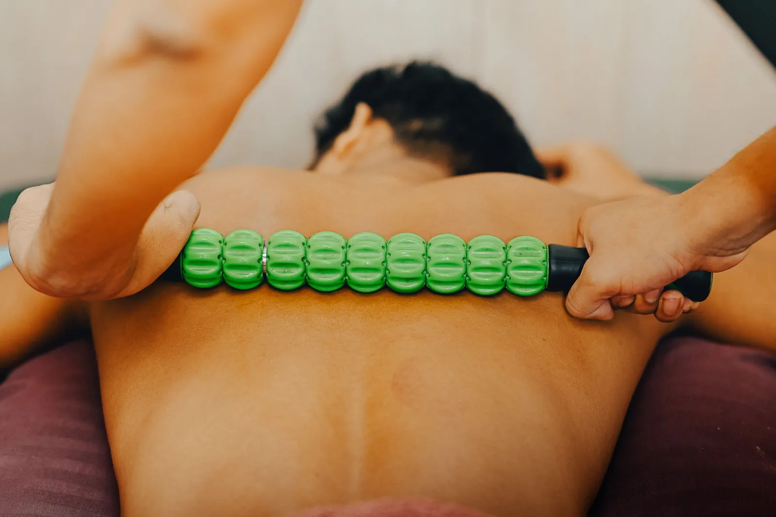 An ABX Physio therapist working a massage roller along a patient's back